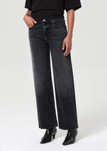 Load image into Gallery viewer, The Harper from AGolde is the perfectly broken-in straight leg. This mid-rise pair comes in a washed-out black with subtle fading and whiskering, offering a lived-in feel from the first wear. Cut from a soft, comfort-stretch regenerative denim, it’s relaxed through the leg with a classic straight fit. Available at aprilmae - a womenswear boutique located in Chiswick west London specialising in contemporary, everyday clothing for women.  Visit our shop on Devonshire Road W4.
