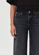 Load image into Gallery viewer, The Harper from AGolde is the perfectly broken-in straight leg. This mid-rise pair comes in a washed-out black with subtle fading and whiskering, offering a lived-in feel from the first wear. Cut from a soft, comfort-stretch regenerative denim, it’s relaxed through the leg with a classic straight fit. Available at aprilmae - a womenswear boutique located in Chiswick west London specialising in contemporary, everyday clothing for women.  Visit our shop on Devonshire Road W4.
