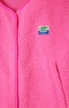 Load image into Gallery viewer, A bright pink fleece gilet with snap button closure, zip pockets, and an American Vintage patch logo on the left chest area. Hoktown hooded fleece by American Vintage in Acid Pink. Available at aprilmae - a womenswear boutique located in Chiswick west London specialising in contemporary, everyday clothing for women.  Visit our shop on Devonshire Road W4 for the latest arrivals.

