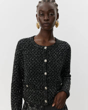 Load image into Gallery viewer, Woman wearing a black textured jacket with silver buttons on a light gray background black glitter cardigan women&#39;s fashion aprilmae chiswick
