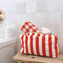 Load image into Gallery viewer, Red and white striped Terry toiletry pouch by Rose in April on a wooden surface with a tiled wall background. Available at aprilmae - a womenswear boutique located in Chiswick west London specialising in contemporary, everyday clothing for women.  Visit our shop on Devonshire Road W4 for the latest arrivals from brands including Rains, Rails, Bellerose, Bonte, Vanessa Bruno, Hartford and Colorful Standard.
